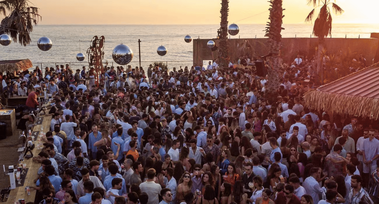 A sunset crowd dancing at a beachfront day party